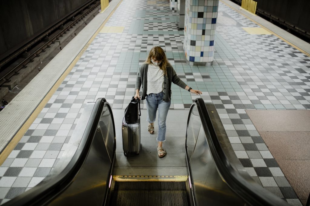 Woman with a suitcase on an escalator during the coronavirus pan