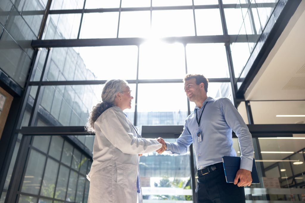 Medical sales representative greeting a doctor with a handshake at the hospital